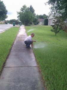 checking a pop-up Rain Bird head during a routine sprinkler repair in Deerfield Beach, FL
